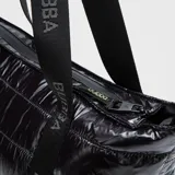 Bolso tipo tote de Bubba, confeccionado en material acolchado brillante de color negro. Cuenta con correas largas con el nombre de la marca estampado, cierre superior y compartimento interno protector para dispositivos electrónicos.