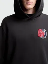 Buzo con capucha Moncler, color negro, de corte regular, con bolsillo frontal tipo canguro y parche circular con logo de la marca en el pecho.
