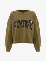 Buzo de algodón color verde oliva con lavado especial, cuello redondo y mangas largas con puños ajustados. Presenta un estampado frontal con la palabra "NEWTONE" en letras negras con efecto puff, y apliques decorativos redondos en el pecho. El ruedo inferior es cortado y deshilachado.