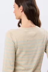 Buzo tejido a rayas de algodón, con cuello redondo y mangas largas. Las franjas combinan tonos beige, celeste y detalles en bordo.
