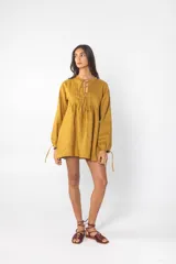 Vestido corto color azul mostaza, con escote con lazos, mangas largas con lazos en los puños y corte holgado.