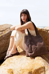 Bolso shopper de cuero vacuno marrón, con diseño de paneles geométricos y detalle de fleco decorativo colgando de un asa.