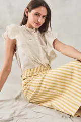 Blusa sin mangas color crema con bordado floral, cuello mao y volados en los hombros.