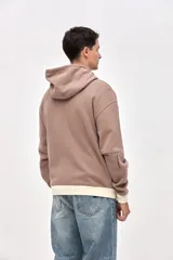 Canguro con cierre frontal metálico, confeccionado en felpa con friza. Presenta capucha con interior en contraste, cuello alto, bolsillos laterales y detalles de bordado de la marca en el pecho y las mangas. Posee un calce relajado con puños y ruedo en contraste.