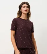 Blusa de pijama de manga corta y cuello redondo, de color marrón oscuro con estampado integral de pequeños corazones blancos. Confeccionada en tejido peach touch de poliéster y elastano.