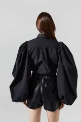 Camisa negra de popelina de algodón con cuello clásico, botones de nácar y mangas largas abullonadas.