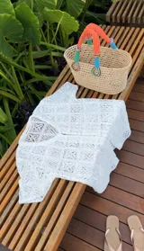 Vestido corto color blanco, tejido calado tipo encaje de algodón, corte recto y suelto, con mangas cortas, botonadura frontal forrada y escote en V.