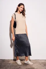 Falda midi de poliéster color negro con estampado de lunares blancos.