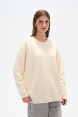 Sweater de tejido de punto color natural, con corte holgado, cuello redondo a la base y mangas largas. Presenta un sutil diseño de bordado con mostacillas en toda la prenda.