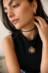 Collar con cordón negro y dije de acero quirúrgico en forma de flor con centro texturizado y pétalos curvos.