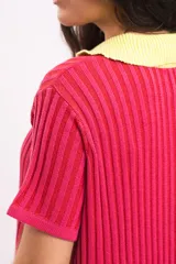Vestido corto de punto acanalado, color fucsia, con cuello polo y solapa en contraste de color amarillo. Presenta mangas cortas y un diseño recto y relajado.