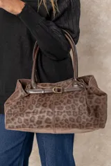 Cartera tipo shopper color chocolate con estampado animal print, confeccionada en material tipo gamuza, con asas cortas rígidas y detalle de cinturón decorativo con hebilla en el frente.