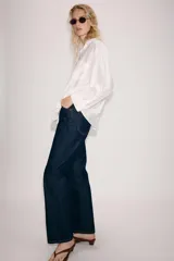 Camisa amplia de cuello solapa con escote en pico y manga larga, en tejido satinado de color bordó. Cuenta con un bolsillo de plastrón en el frente y un diseño holgado.