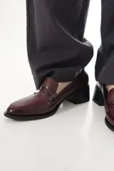 Mocasines Emilia de cuero vacuno en color bordó, con diseño de punta almendrada, detalle de antifaz con textura texturizada en la parte superior y tacón de bloque ancho en color negro.