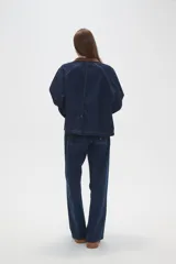 Campera de jean azul oscuro con cuello y puños de pana en color marrón. Presenta cierre frontal, costuras a la vista y detalles de botones metálicos en los puños.