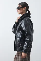 Campera de cuero sintético con acabado satinado, silueta relajada y elástico en la cintura. Presenta cuello con textura de piel sintética, cierre frontal y bolsillos laterales.