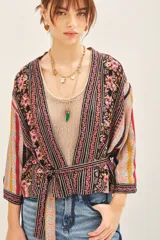 Kimono corto con mangas 3/4, confeccionado en viscosa estampada con diseño floral y rayas verticales. Presenta un cierre frontal cruzado con lazo ajustable en la cintura y forrería interior.