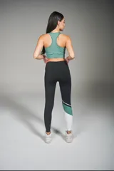 Calza deportiva larga negra con recortes en blanco y verde en la parte inferior de una pierna.