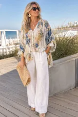 Camisa de manga ancha con elástico en los puños, confeccionada en una mezcla de algodón y lino, con diseño estampado floral en tonos azules y amarillos.