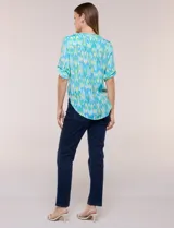 Blusa camisera de estilo casual confeccionada en mezcla de rayón y poliéster, con estampado multicolor en tonos turquesa, verde y celeste. Presenta escote en V con cuello mao, abotonadura frontal con botones nacarados, bolsillos aplicados en el pecho y mangas tres cuartos con presilla para arremangar. Cuenta con ruedo curvo y picos frontales diseñados para anudar en la cintura.