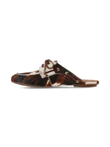 Zuecos Arno destalonados confeccionados en cuero con pelo con estampado animal print tipo vaca en tonos marrones, negros y blancos. Presentan diseño de inspiración náutica con cordones de cuero cruzados y ojalillos metálicos dorados.