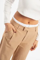 Pantalón de vestir color beige, de corte recto y tiro alto, con pretina blanca.