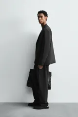 Pantalón de traje regular fit confeccionado en popelín de algodón. Presenta cintura con pliegues frontales, bolsillos laterales y bolsillos traseros de vivo con botón. El bajo tiene acabado con vuelta y el cierre es frontal con cremallera y botón.