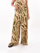 Pantalón palazzo estampado con motivos de hojas en tonos beige y verde.