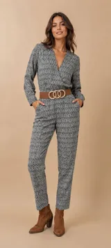 Enterito de corte cruzado con escote en V, manga larga y pantalón de corte recto. Presenta un estampado geométrico en tonos gris y blanco, con bolsillos laterales.