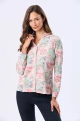 Camisa de jersey de algodón suave, con estampado floral en tonos pastel de rosado, verde y lila. Tiene cuello camisero, cierre frontal con botones y mangas largas.