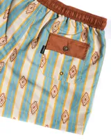 Short de baño de microfibra con estampado de rayas verticales en tonos celeste y beige, con motivos geométricos en color ocre. Tiene cintura elastizada marrón con cordón ajustable, dos bolsillos laterales y uno trasero.
