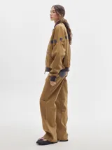 Pantalón jean de tiro alto y corte pinzado, con perneras de caída suelta y levemente anchas en el bajo. Posee pasador con hebilla en la parte trasera.