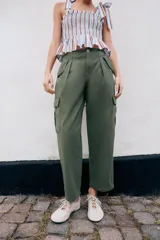 Pantalón cargo de tiro medio con pinzas delanteras, bolsillos laterales de plastrón y cierre frontal con cremallera y botón. Presenta una pernera holgada que se estrecha ligeramente hacia el bajo.
