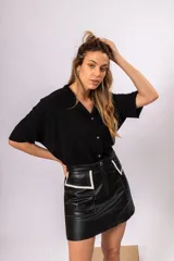 Minifalda negra de cuero con bolsillos frontales y detalles en contraste color hueso.