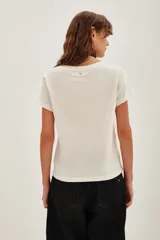 Remera de algodón color crudo con estampa frontal gráfica de estilo pixelado que representa un rostro con detalles en fucsia y amarillo.