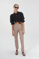 Pantalón de cuero color beige, de corte recto, tiro medio y tajos en el ruedo.