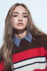 Sweater de tejido de punto con diseño de rayas horizontales en tonos rojo, blanco, azul marino y marrón. Presenta cuello redondo, mangas largas y un calce relajado.