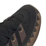 Championes adidas modelo Adimatic, de diseño robusto inspirado en el skate de los años 90. Presenta un exterior de gamuza negra con las icónicas tres tiras laterales en color marrón, cordones gruesos y una suela de goma dentada con patrón en zigzag.