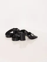 Sandalia negra de cuero vacuno con taco cuadrado y detalle de apliques plateados en la capellada.