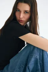 Remera negra de manga corta con cuello redondo fino, confeccionada en punto de algodón elástico.