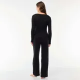 Pijama de dos piezas en color negro, confeccionado en tejido de punto acanalado. Incluye una remera de manga larga con cierre frontal de botones y un pantalón de corte recto y holgado.