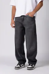 Jean de corte baggy y fit oversize, confeccionado en denim de algodón con lavado efecto gastado en color gris oscuro. Presenta costuras reforzadas en la zona de las rodillas y diseño de cinco bolsillos.