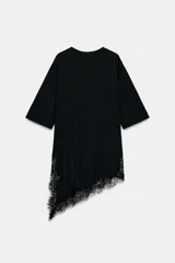 Camiseta de algodón de corte regular, color marrón oscuro o negro, con cuello redondo y manga corta. Presenta un bajo asimétrico con aplicación de encaje negro a tono.