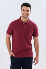 Remera polo lisa de piqué en color bordó, con cuello camisero, cierre frontal con botones y mangas cortas.