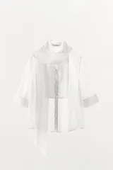 Camisa blanca de tejido semitransparente ZARA Woman Collection, con cuello redondo, manga corta y detalle de pañuelo integrado en el mismo tejido al cuello. Cierre frontal con botones.