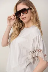 Remera de algodón color blanco, con cuello redondo y mangas cortas holgadas que presentan detalles de encaje broderie.