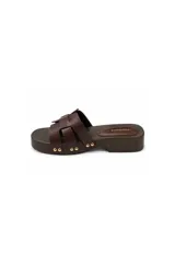Sandalia tipo zueco Paddock de color negro, con plataforma baja de aspecto amaderado y tiras entrelazadas en el empeine. Presenta detalles de tachas metálicas doradas en los laterales y plantilla acolchada.