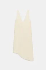 Vestido midi de color beige con escote en pico pronunciado y tirantes anchos. Presenta un diseño de jacquard con patrón sutil y un bajo con acabado asimétrico.