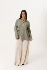 Camisa verde militar de manga larga con silueta oversize, dos bolsillos delanteros y corte levemente más largo en la espalda. Escote en V abotonado con detalle de galón picot a lo largo de la cartera y botones a tono. Isotipo bordado en la parte trasera.