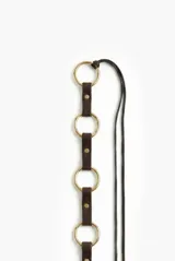 Cinturón de cuero marrón con estructura de aros metálicos dorados unidos por tiras de cuero y remaches, acompañado de tiras finas colgantes.